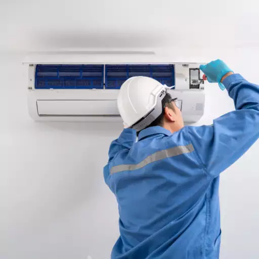 A man in a hard hat is working on a ductless air conditioner.